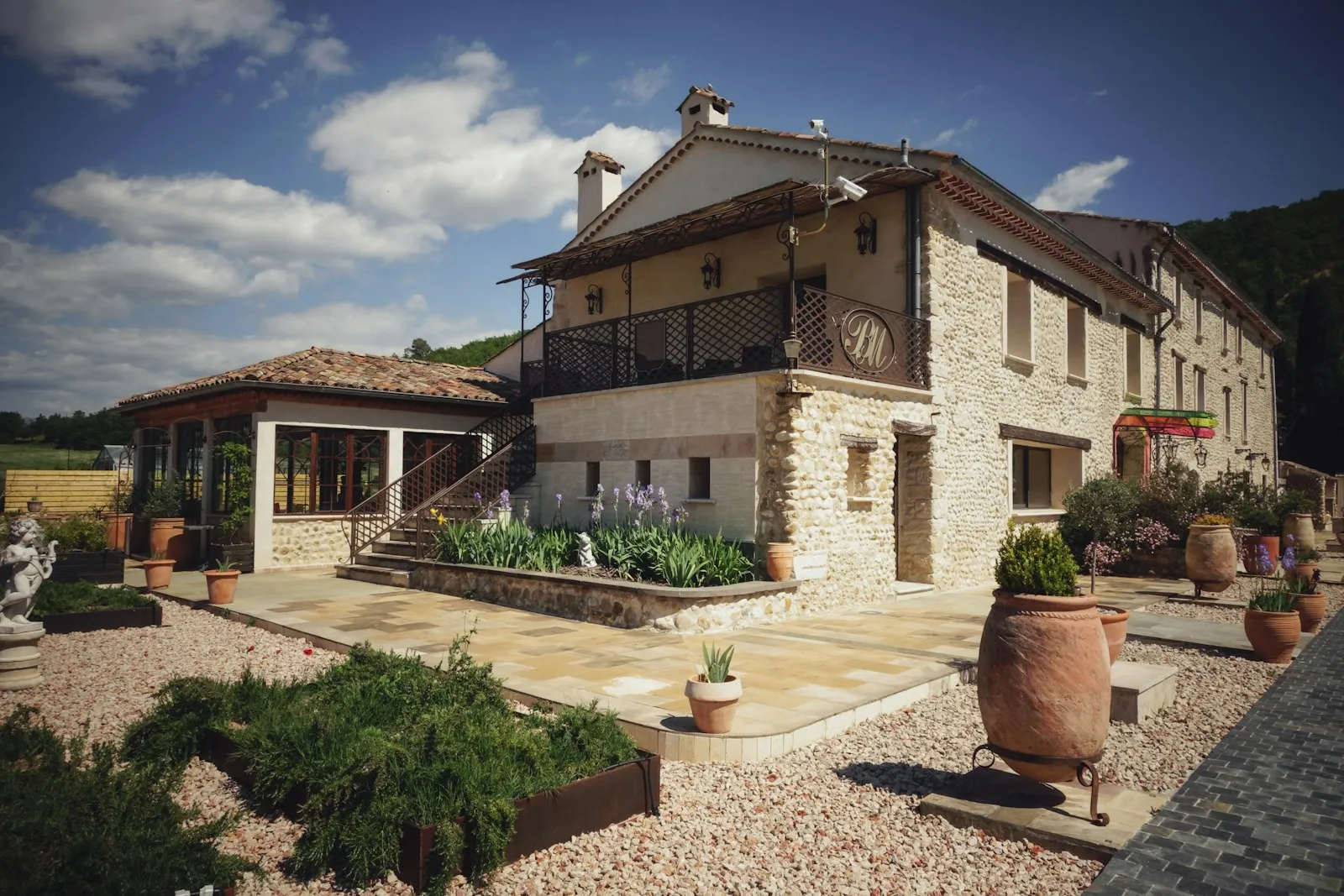 Maison de pierre rénovée, terrasse fleurie et balcon en bois