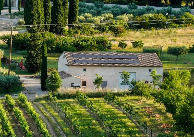Grange au toit couvert de panneaux photovoltaïques, entre vignes et cyprès, à Lourmarin